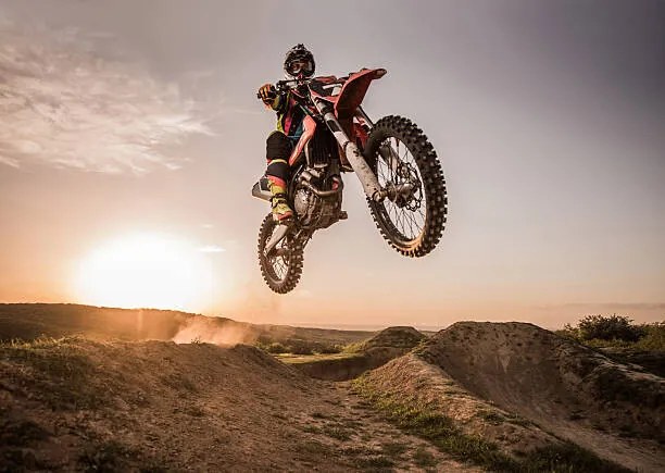 Foto Motocross rider performing high jump at sunset., skynesher