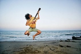 Foto Mixed Race man playing guitar and jumping at beach, Peathegee Inc, (40 x 26.7 cm)